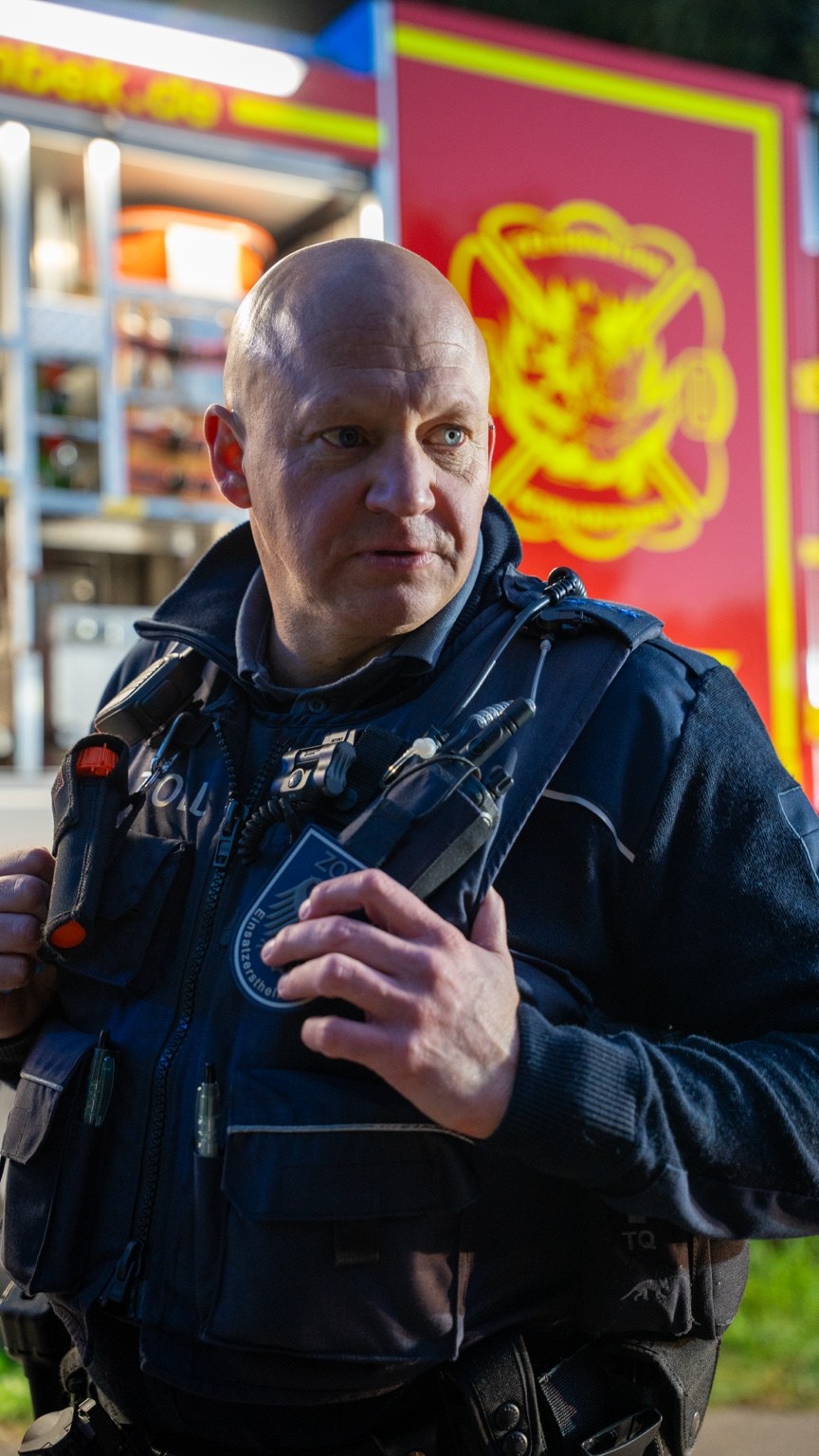 Porträt eines Mannes in Zoll-Einsatzkleidung vor einem Feuerwehrfahrzeug